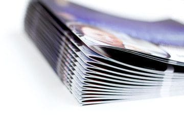 A stack of BOOKLETS/SOUVENIR JOURNALS on a white surface.